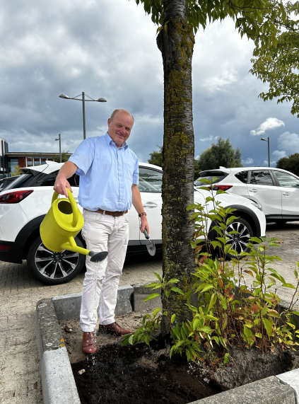 Wethouder Remery geeft water aan een boomtuintje